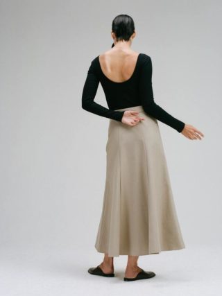 CAES model wearing a black body and a beige skirt