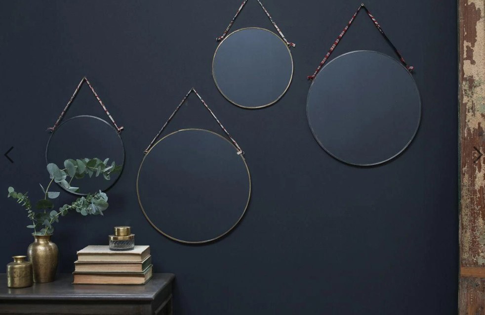 Brass mirrors hung on a dark wall