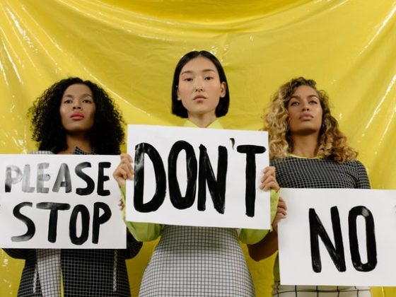 MeToo movement. Three women are standing holding signs advocating against sexual harassment