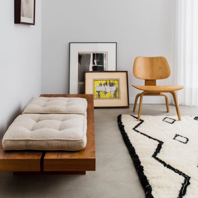 A modern and minimalist interior. A bright space with wooden seating and a moroccan rug.