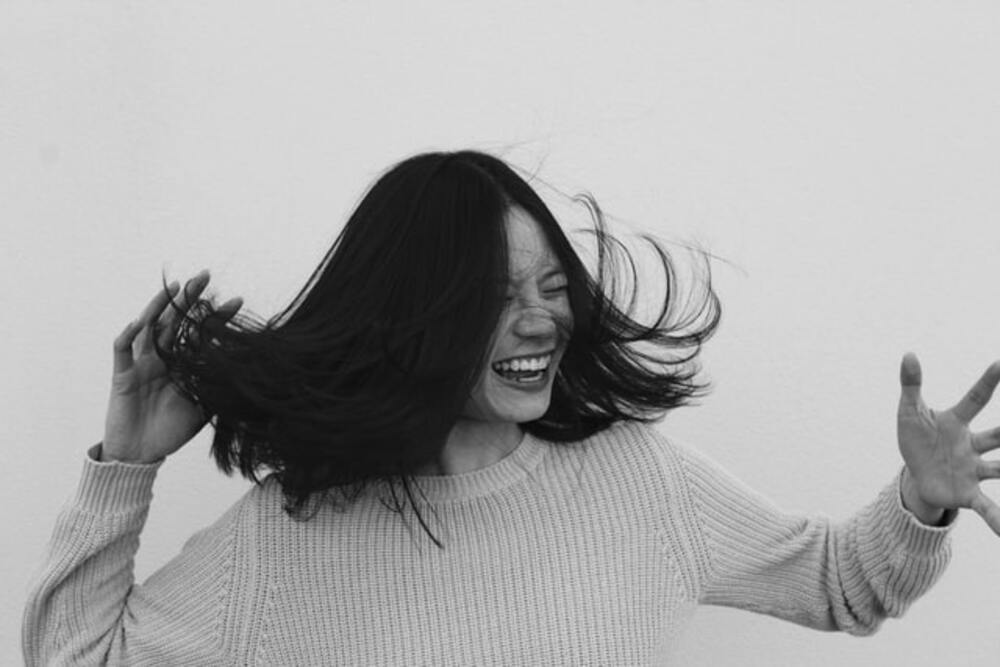 Benefits of laughter on your body and sould. Image of a girl laughing with the wind blowing her hair.