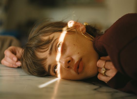 image of female laying on the floor with a light streak on her face.