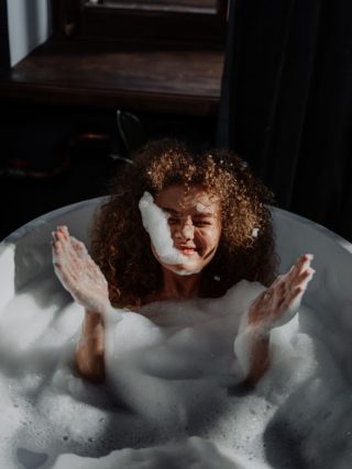 Laughing as a form of self-care : a woman laughing while taking a bubble bath