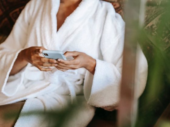 Woman in white robe scrolling on her phone